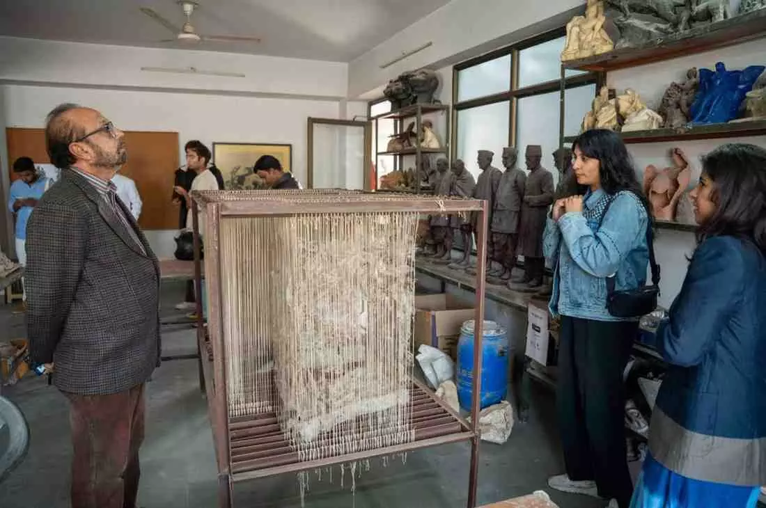 पिंक सिटी स्टूडियो में एक कलाकृति के पास चर्चा करते कलाकार और दर्शक पिंक सिटी स्टूडियो में एक कलाकृति के पास चर्चा करते कलाकार और दर्शक