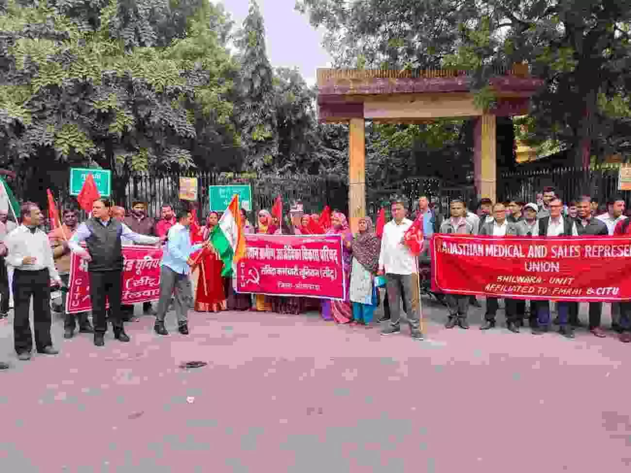 भीलवाड़ा कलेक्ट्रेट के बाहर प्रदर्शन करते संयुक्त श्रमिक मोर्चा के कार्यकर्ता और बैनर थामे प्रदर्शनकारी।