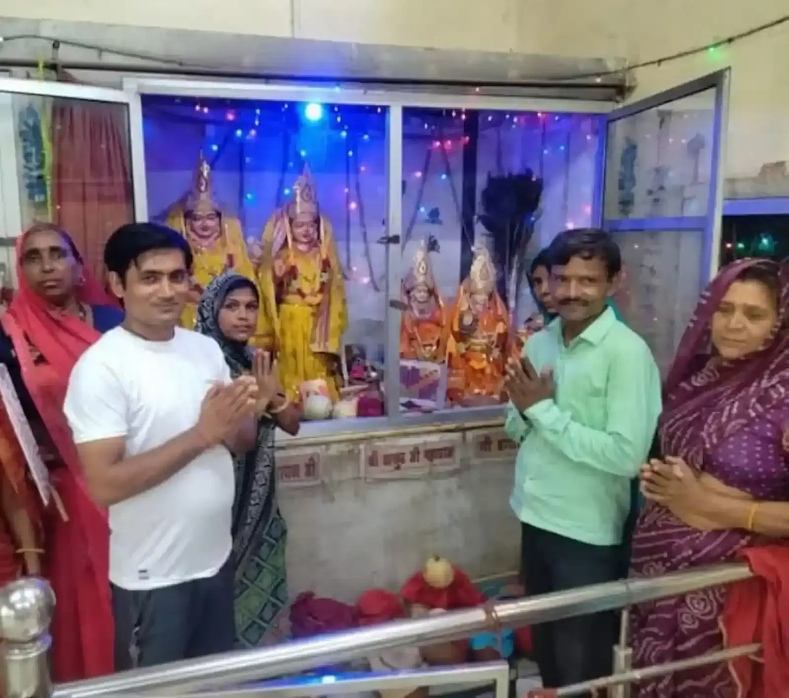 भुसावर के मंदिर में फूलों से सजी राधा कृष्ण की मूर्ति और पूजा करते श्रद्धालु।