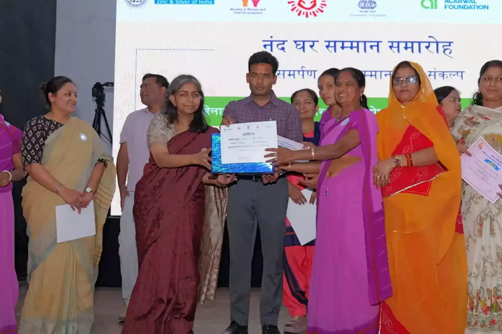 चित्तौड़गढ़ में आयोजित समारोह के दौरान मंच पर अतिथियों द्वारा आंगनवाड़ी कार्यकर्ताओं को सम्मानित करते हुए दृश्य।