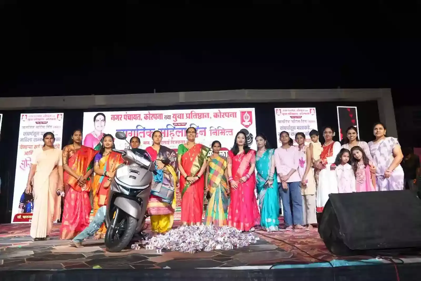 कोरपना के महिला सम्मान समारोह में मंच पर उपस्थित अतिथियों और सत्कार हेतु एकत्रित महिलाओं का समूह दृश्य।