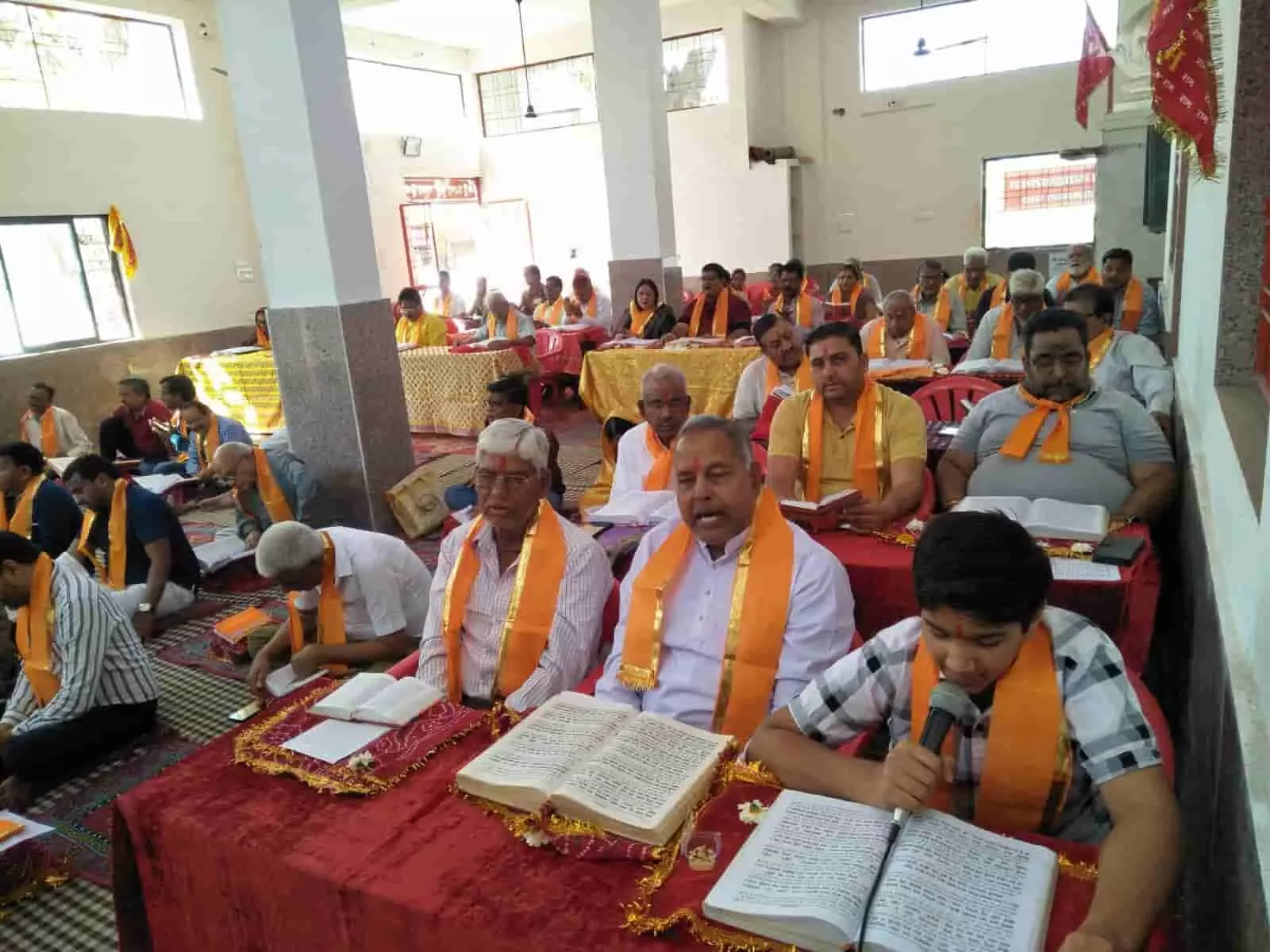 फतहनगर के हनुमान मंदिर में सामूहिक रामायण पाठ के दौरान पोथी पढ़ते हुए श्रद्धालु और मुख्य व्यासपीठ के दृश्य।