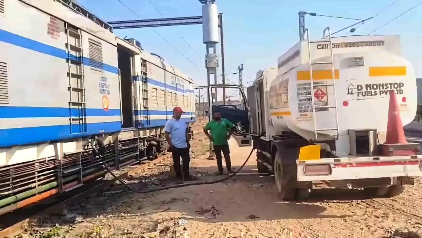 रेलवे ट्रैक पर खड़ा डीजल इंजन वाला टॉवर वैगन जिसमें मोबाइल डिस्पेंसर से ईंधन भरा जा रहा है।