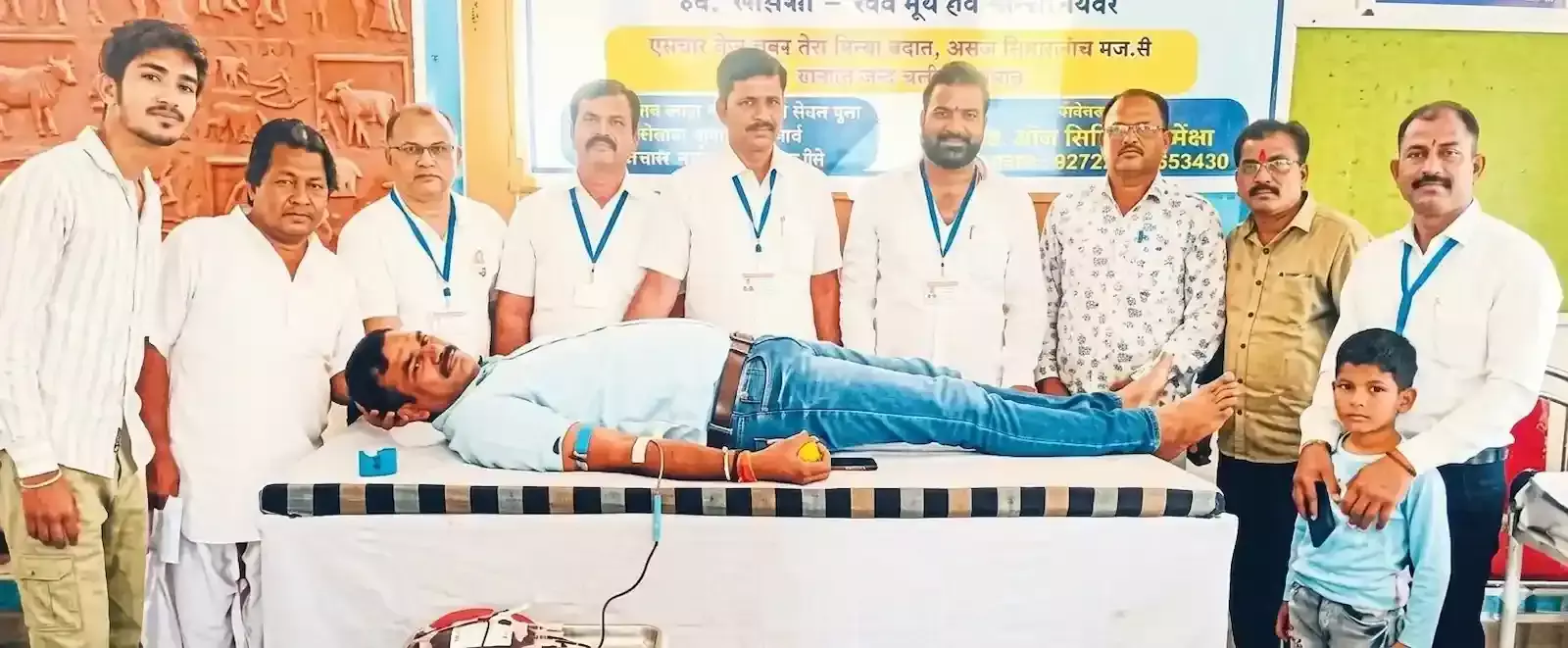 मोलेला के स्वास्थ्य शिविर में बेड पर लेटकर रक्तदान करता युवक और पास खड़े चिकित्साकर्मी।