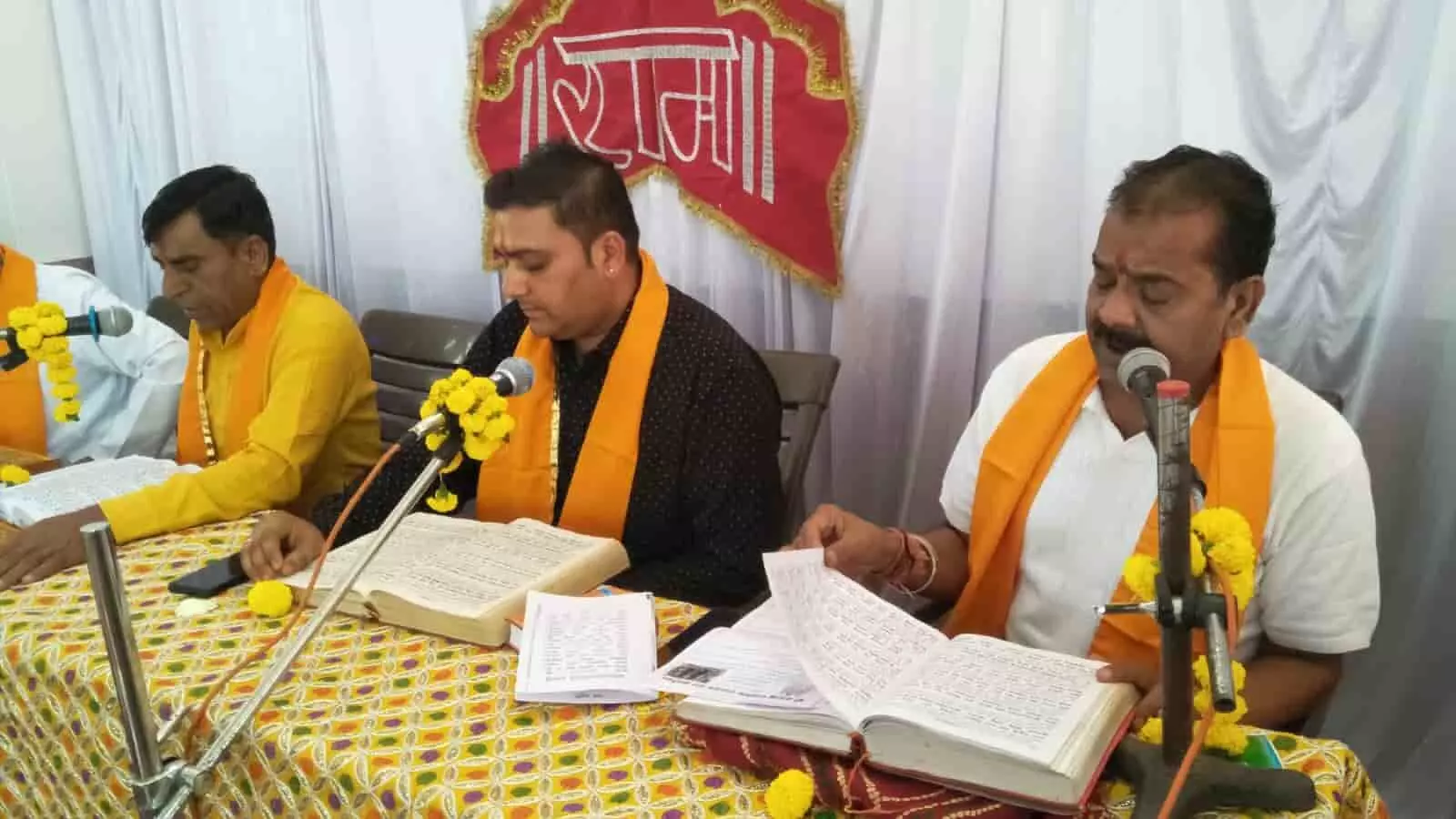 हनुमान मंदिर में सामूहिक रामायण पाठ के दौरान व्यासपीठ पर बैठकर धार्मिक ग्रंथों का वाचन करते श्रद्धालु हनुमान मंदिर में सामूहिक रामायण पाठ के दौरान व्यासपीठ पर बैठकर धार्मिक ग्रंथों का वाचन करते श्रद्धालु