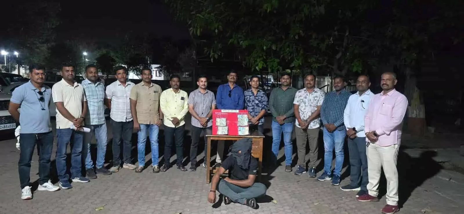 लातूर पुलिस की हिरासत में खड़ा धोखाधड़ी का आरोपी और मेज पर रखी बरामद नकदी