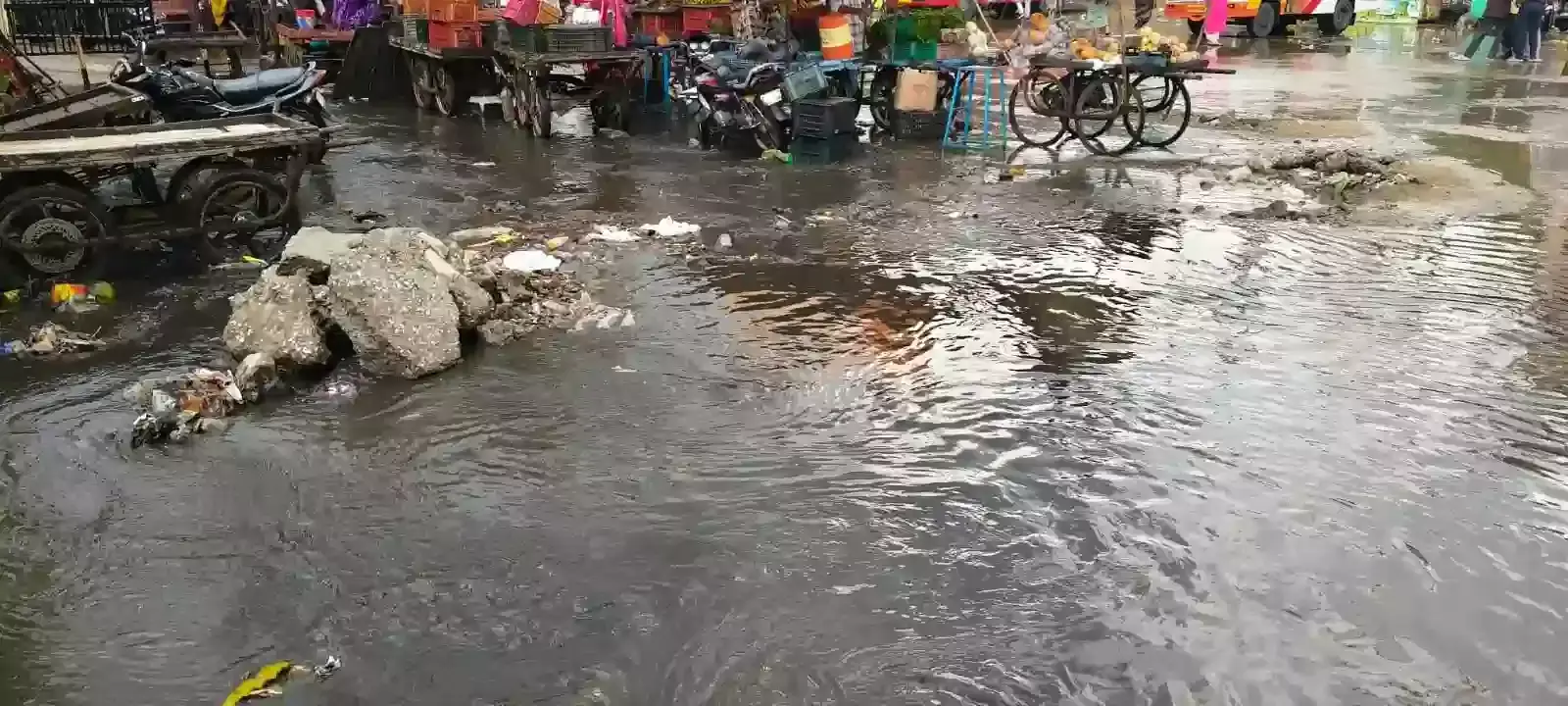 आमेट मुख्य बस स्टैंड की सड़क पर नाले का गंदा पानी और जलभराव के बीच से गुजरते हुए वाहन और राहगीर आमेट मुख्य बस स्टैंड की सड़क पर नाले का गंदा पानी और जलभराव के बीच से गुजरते हुए वाहन और राहगीर
