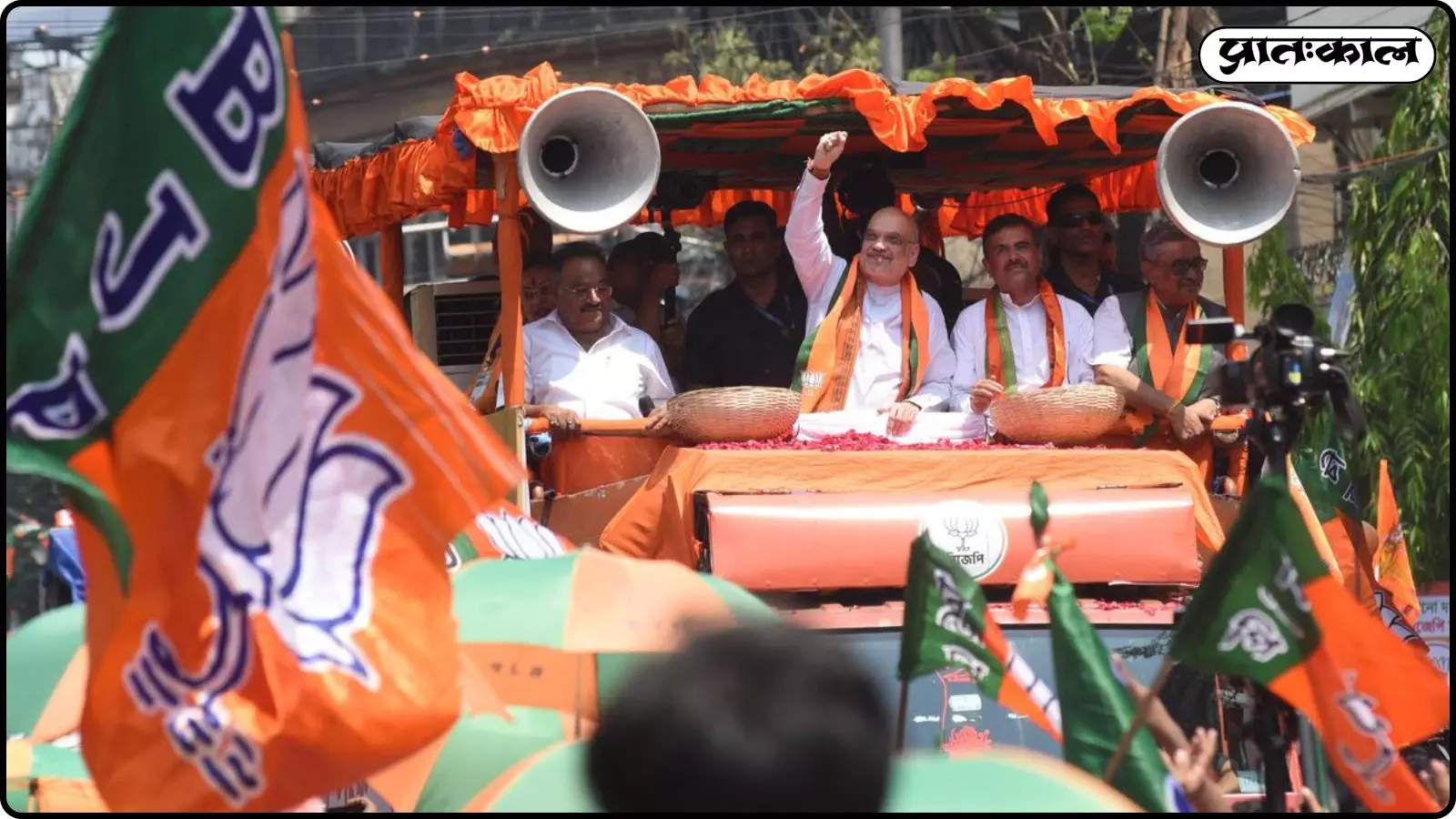 भगवा झंडों के बीच एक खुले वाहन पर सवार होकर अमित शाह जनता की ओर हाथ हिला रहे हैं। भगवा झंडों के बीच एक खुले वाहन पर सवार होकर अमित शाह जनता की ओर हाथ हिला रहे हैं।
