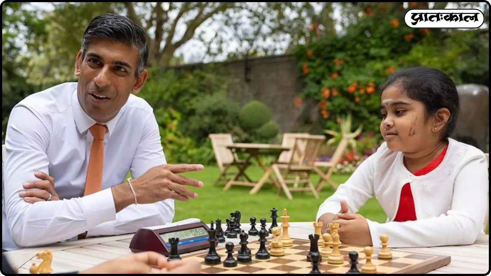 सफेद शर्ट पहने रिषि सुनेक और बोधना शिवानंदन गार्डन में मेज पर शतरंज खेल रहे हैं। सफेद शर्ट पहने रिषि सुनेक और बोधना शिवानंदन गार्डन में मेज पर शतरंज खेल रहे हैं।