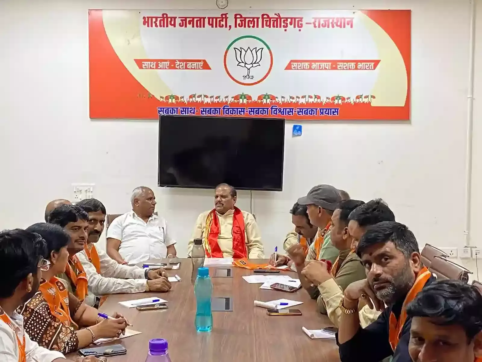 चित्तौड़गढ़ भाजपा जिला कार्यालय में स्थापना दिवस बैठक के दौरान मंच पर बैठे पार्टी पदाधिकारी और उपस्थित कार्यकर्ता।
