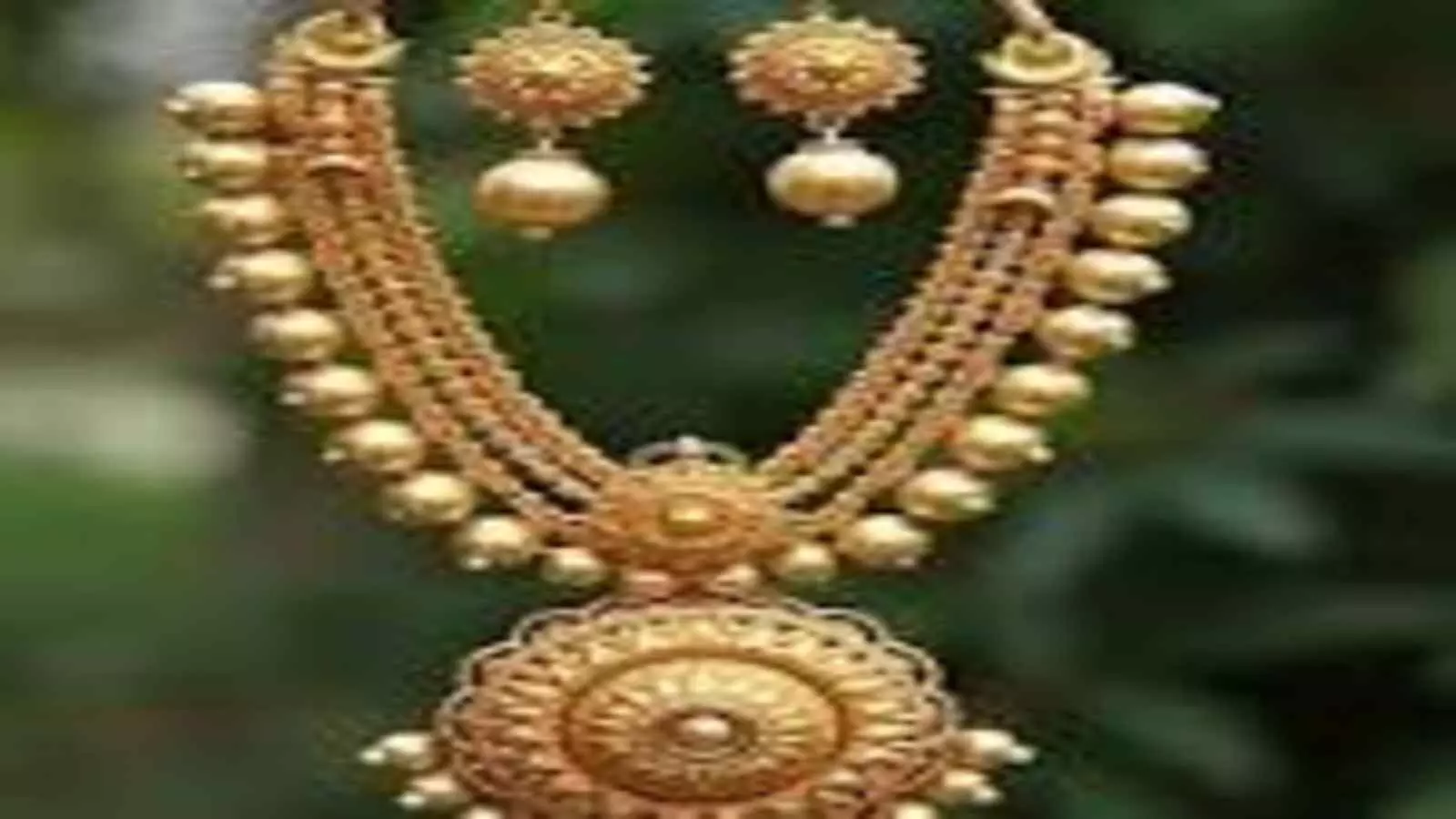 सुनहरे रंग का भारी सोने का हार और कान के झुमके गहरे बैकग्राउंड पर रखे हुए। सुनहरे रंग का भारी सोने का हार और कान के झुमके गहरे बैकग्राउंड पर रखे हुए।