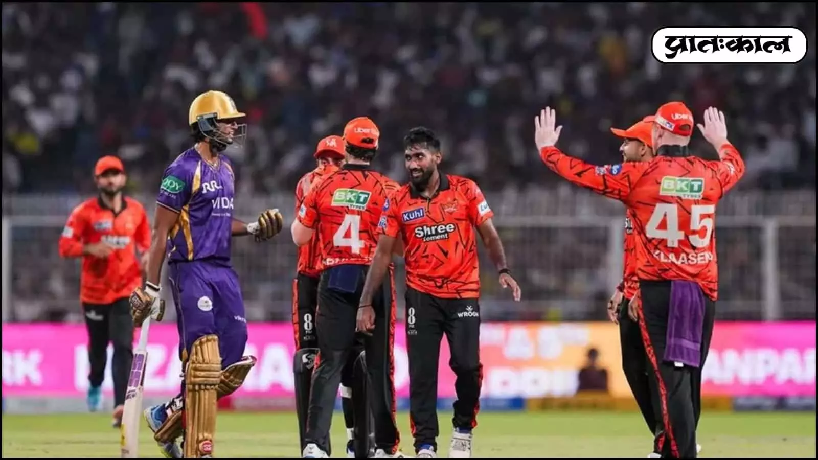 क्रिकेट के मैदान पर नारंगी जर्सी पहने हैदराबाद के खिलाड़ी बैंगनी जर्सी वाले बल्लेबाज के सामने जश्न मना रहे हैं। क्रिकेट के मैदान पर नारंगी जर्सी पहने हैदराबाद के खिलाड़ी बैंगनी जर्सी वाले बल्लेबाज के सामने जश्न मना रहे हैं।