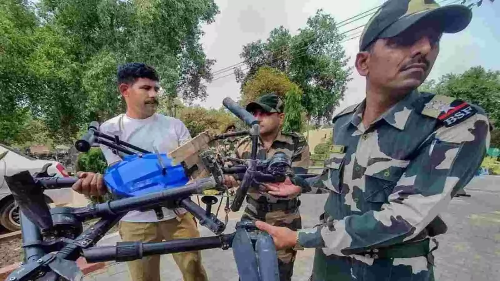 वर्दी में खड़े बीएसएफ जवान क्षतिग्रस्त नीले रंग के ड्रोन को हाथों में पकड़े हुए हैं। वर्दी में खड़े बीएसएफ जवान क्षतिग्रस्त नीले रंग के ड्रोन को हाथों में पकड़े हुए हैं।