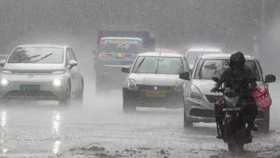 बारिश के दौरान सड़क पर चलते हुए कार और मोटरसाइकिल सवार व्यक्ति। बारिश के दौरान सड़क पर चलते हुए कार और मोटरसाइकिल सवार व्यक्ति।