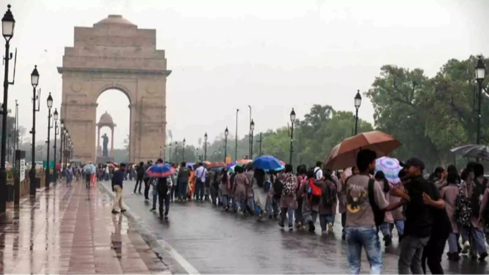 इंडिया गेट के सामने बारिश में छाता लेकर चलते लोग और स्कूली छात्र। इंडिया गेट के सामने बारिश में छाता लेकर चलते लोग और स्कूली छात्र।