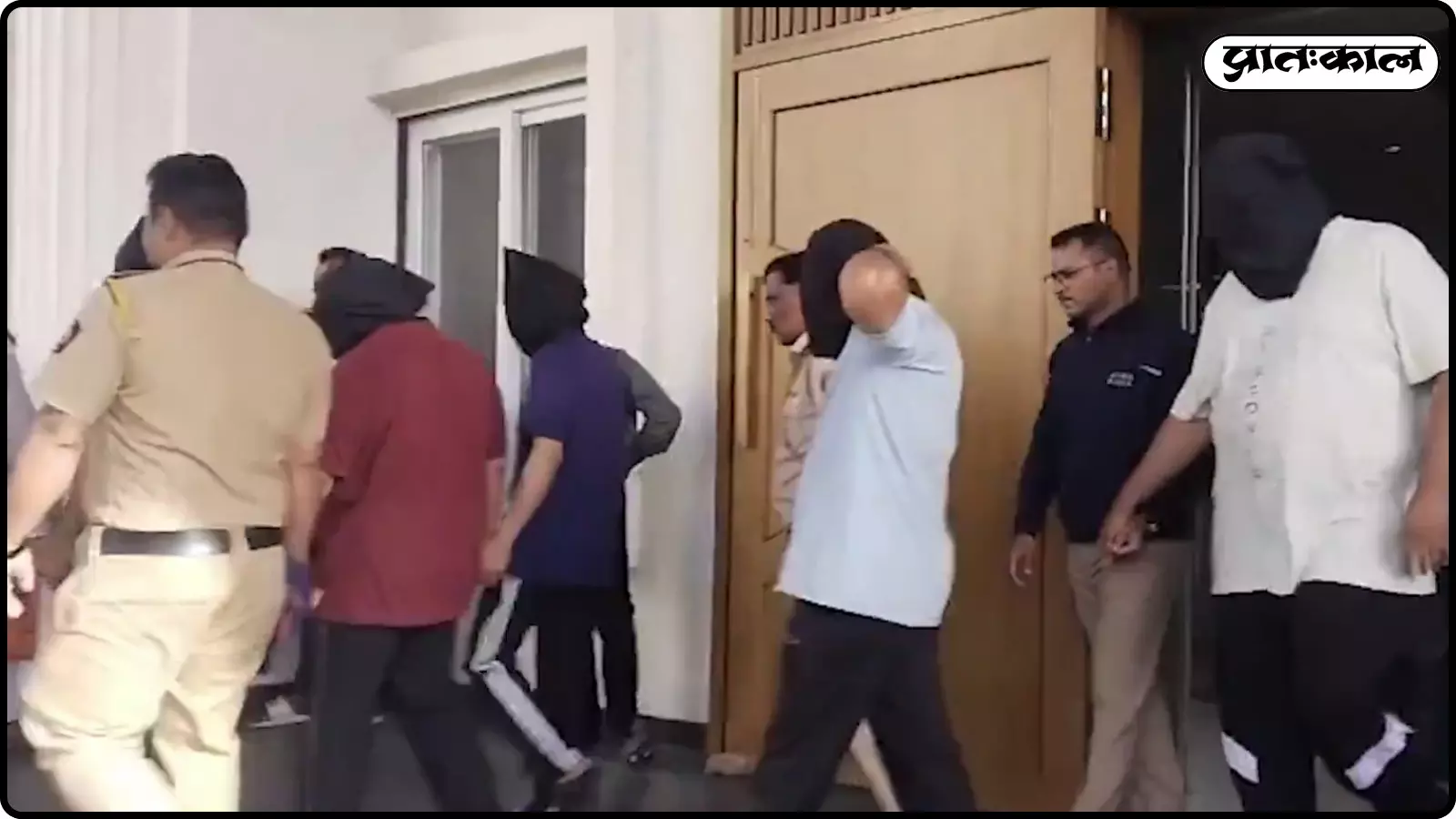 पुलिस कर्मियों के साथ लाइन में चलते हुए चेहरा ढके हुए छह गिरफ्तार आरोपी पुरुष। पुलिस कर्मियों के साथ लाइन में चलते हुए चेहरा ढके हुए छह गिरफ्तार आरोपी पुरुष।