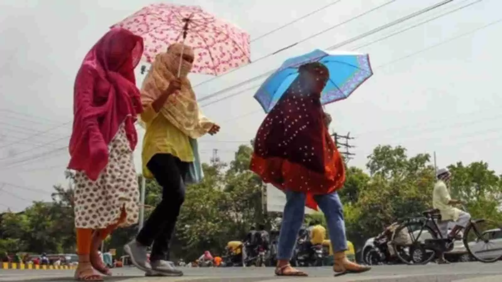धूप से बचाव के लिए महिलाएं छाता लेकर और सिर ढंककर सड़क पर पैदल चल रही हैं। धूप से बचाव के लिए महिलाएं छाता लेकर और सिर ढंककर सड़क पर पैदल चल रही हैं।