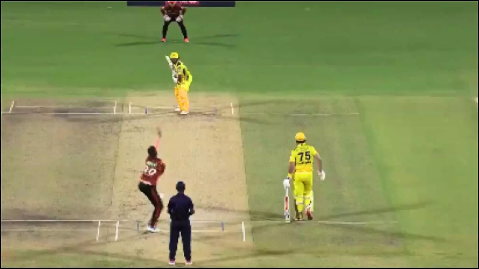 क्रिकेट के मैदान पर गेंदबाज बॉल डाल रहा है और बल्लेबाज शॉट खेलने के लिए तैयार खड़ा है।