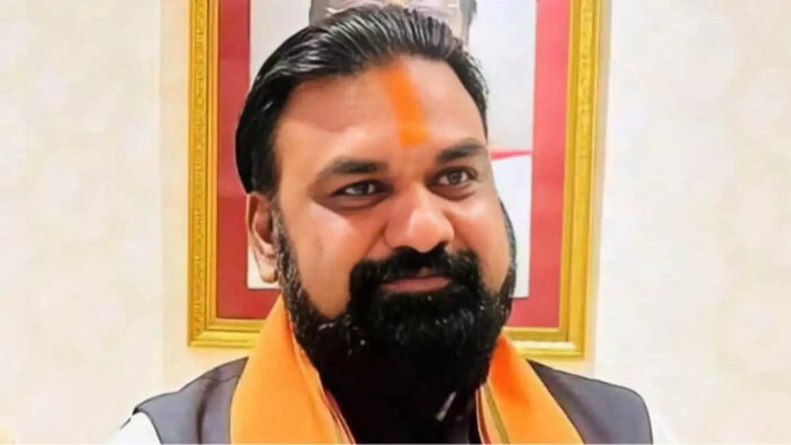 नारंगी दुपट्टा पहने हुए सम्राट चौधरी की एक क्लोजअप फोटो जिसमें वे मुस्कुरा रहे हैं।