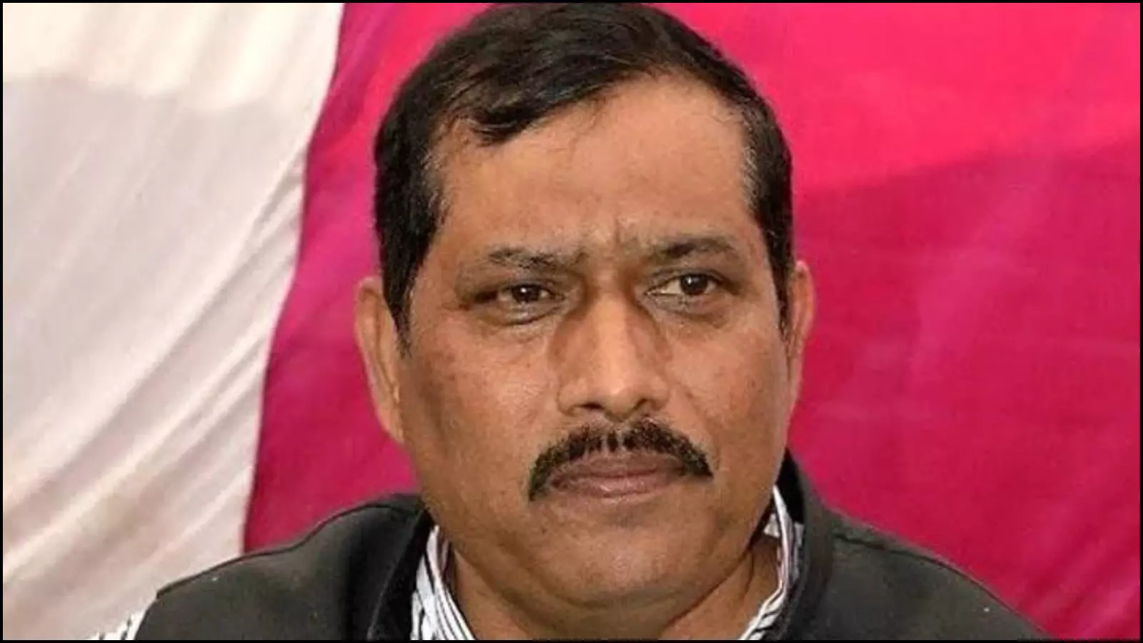 कैमरे की ओर देखते हुए भाजपा विधायक श्याम प्रकाश गुलाबी पृष्ठभूमि के सामने अपनी बात रखते हुए।