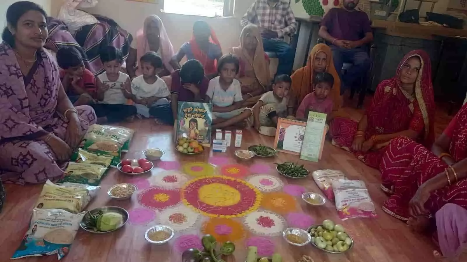 नंदघर आंगनवाड़ी केंद्र में जमीन पर रखी खाद्य सामग्री के पास बैठी महिलाएं और बच्चे पोषण पखवाड़ा कार्यक्रम में। नंदघर आंगनवाड़ी केंद्र में जमीन पर रखी खाद्य सामग्री के पास बैठी महिलाएं और बच्चे पोषण पखवाड़ा कार्यक्रम में।
