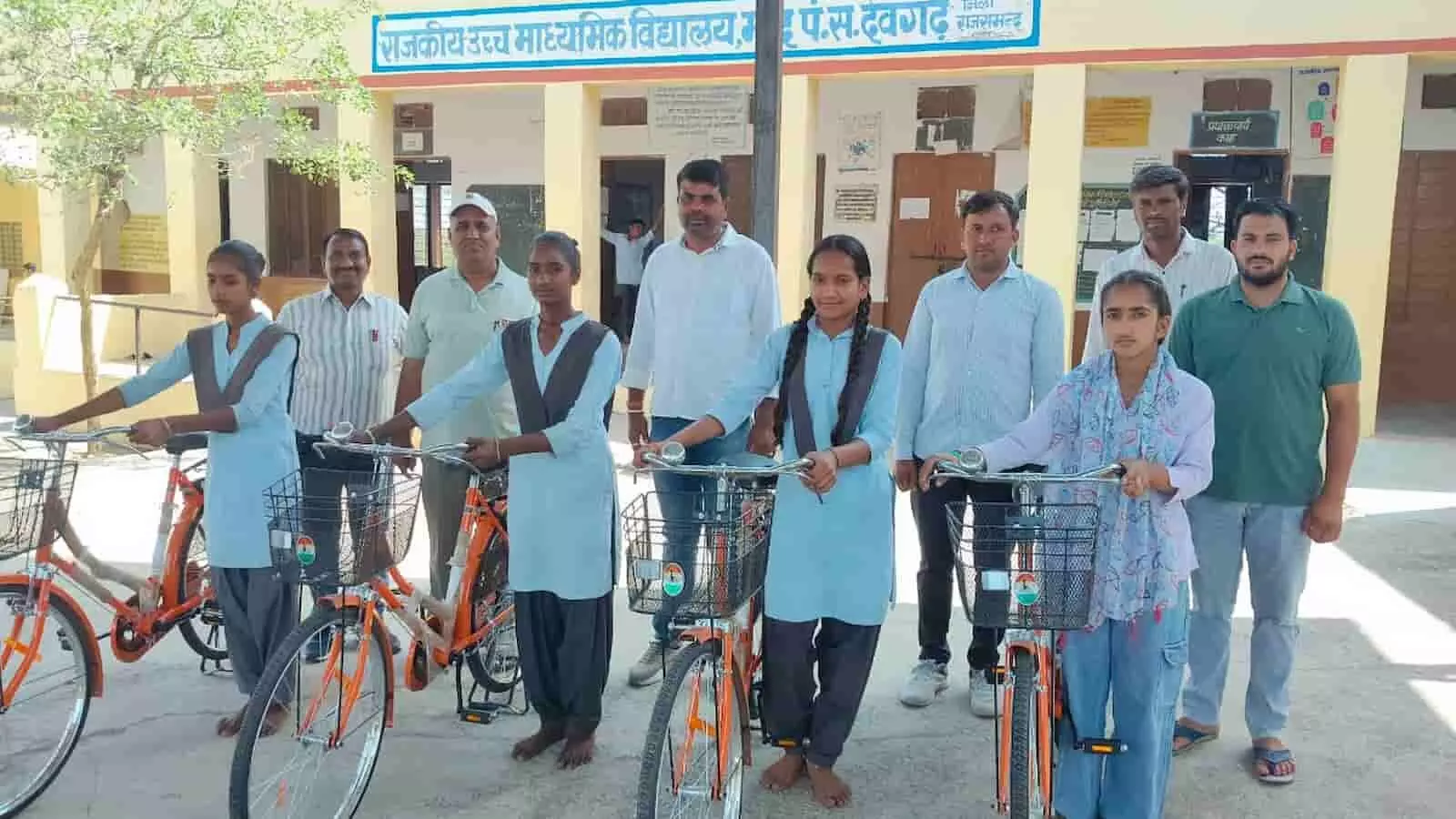 राजकीय स्कूल की चार छात्राएं अपनी नई साइकिलों के साथ स्कूल स्टाफ के साथ खड़े होकर फोटो खिंचवा रही हैं।