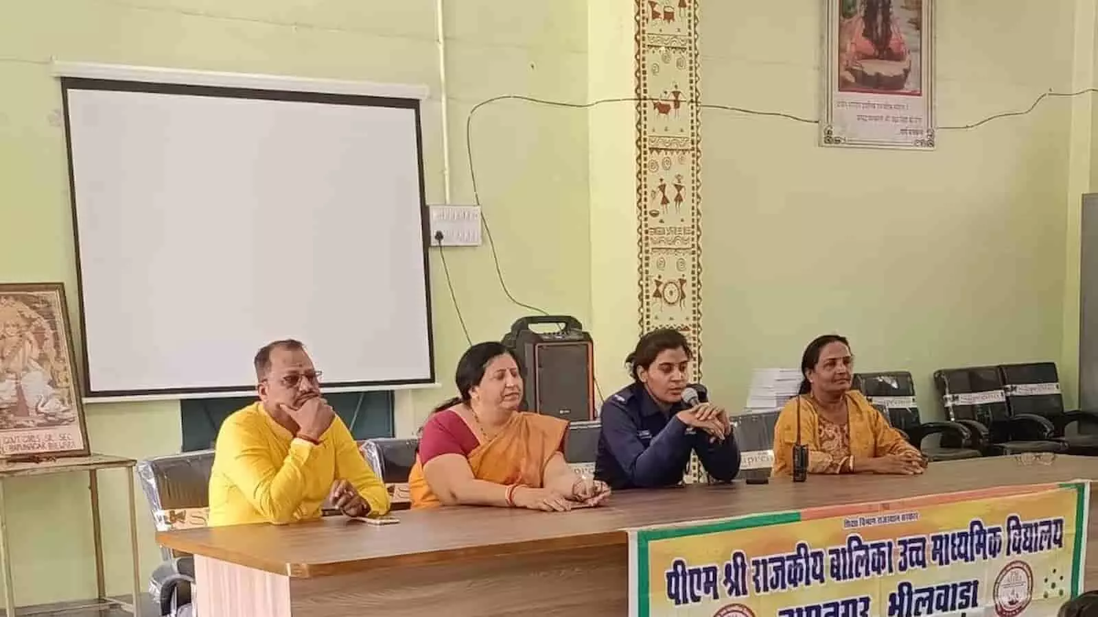 क्लासरूम में बैठी छात्राओं का समूह और मंच पर महिला सुरक्षा पर जानकारी देती पुलिस अधिकारी। क्लासरूम में बैठी छात्राओं का समूह और मंच पर महिला सुरक्षा पर जानकारी देती पुलिस अधिकारी।