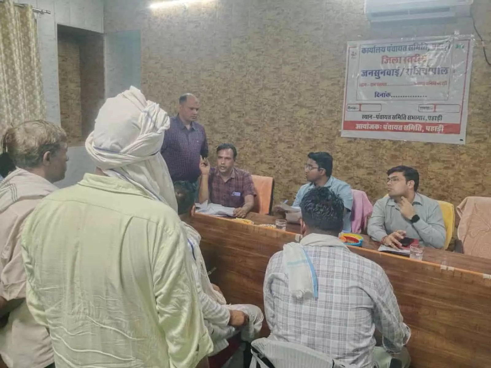 पंचायत समिति कार्यालय के भीतर मेज पर बैठे अधिकारी और सामने खड़े ग्रामीण जन-सुनवाई के दौरान। पंचायत समिति कार्यालय के भीतर मेज पर बैठे अधिकारी और सामने खड़े ग्रामीण जन-सुनवाई के दौरान।