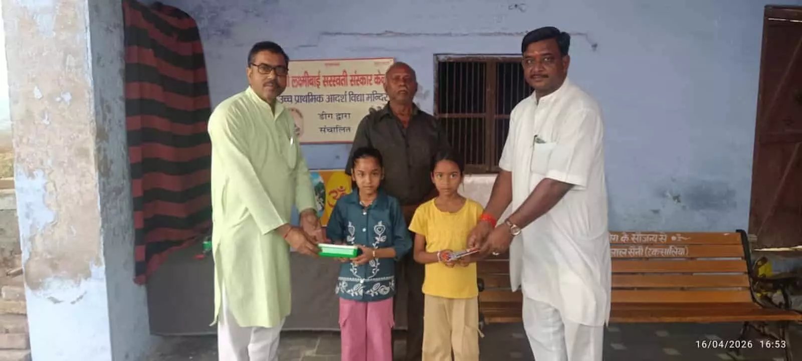 विद्यालय परिसर में दो छात्राओं को पुरस्कार देते हुए तीन पुरुष डीग में परीक्षा परिणाम के संदर्भ में। विद्यालय परिसर में दो छात्राओं को पुरस्कार देते हुए तीन पुरुष डीग में परीक्षा परिणाम के संदर्भ में।