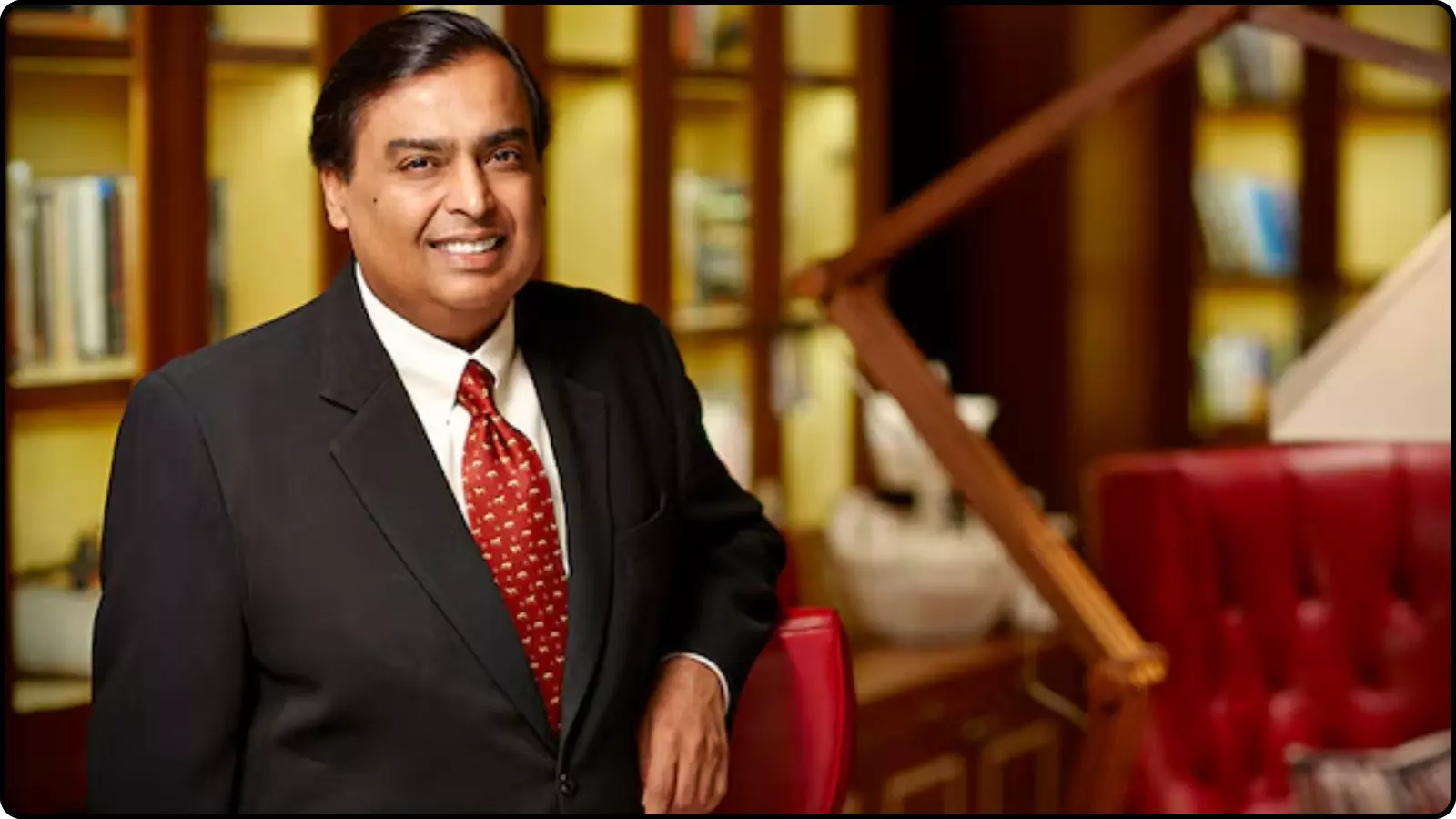काले कोट और लाल रंग की टाई पहने हुए मुस्कुराते मुकेश अंबानी मुंबई के कार्यालय के संदर्भ में।