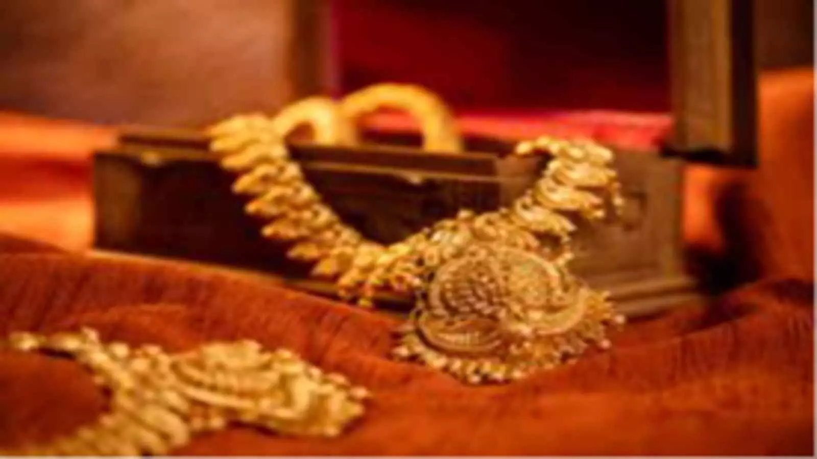 एक लकड़ी के सजावटी बक्से में रखे हुए 22 कैरेट सोने के भारी नक्काशीदार हार और आभूषण।