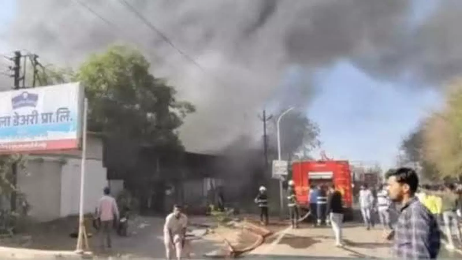 धुएं के गुबार के बीच दमकल की गाड़ी और बचाव कर्मी लातूर फैक्ट्री में आग बुझाते हुए।