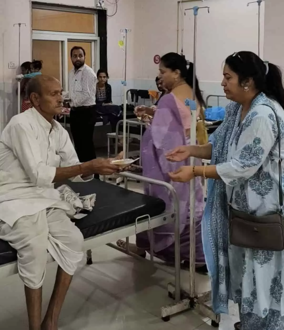 बारां के राजकीय चिकित्सालय में बेड पर लेटे मरीज को भोजन देती महिलाएं।