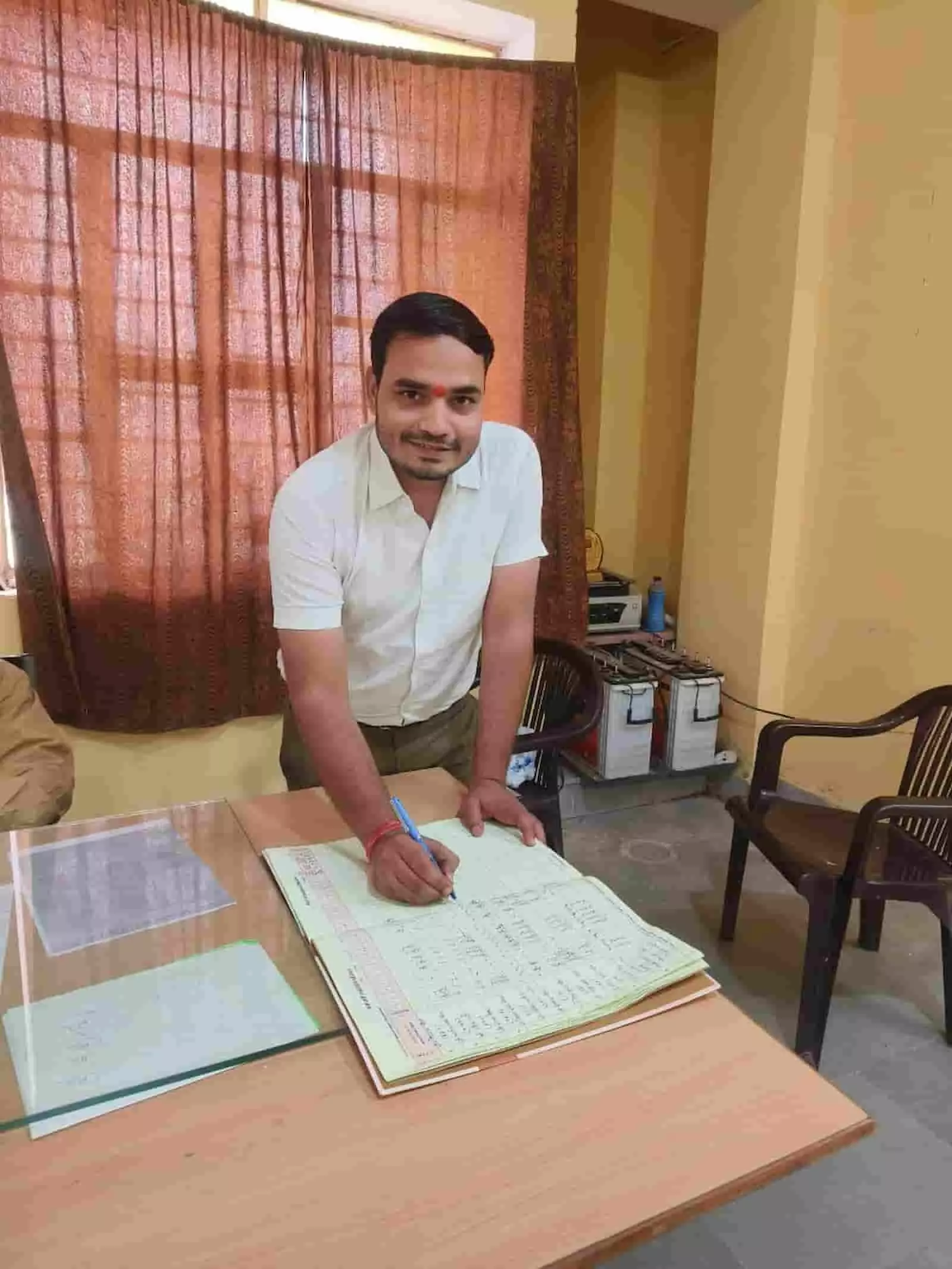 कार्यालय की मेज पर रजिस्टर में प्रविष्टि करते नितिन पाण्डेय पदोन्नति के संदर्भ में।