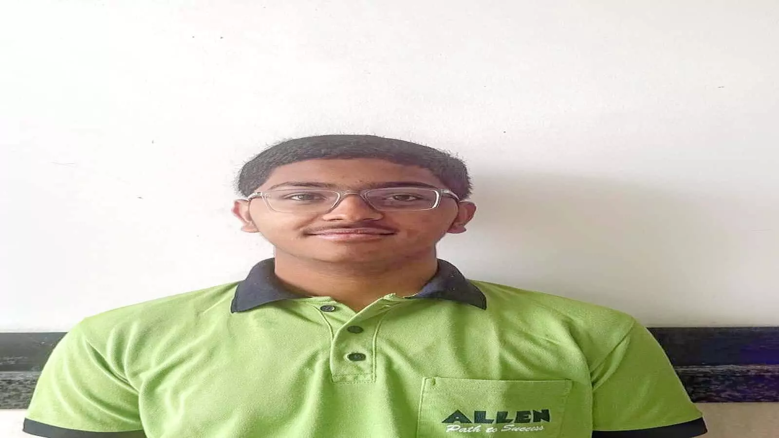 चश्मा पहने हुए छात्र अर्नव कैलाश कुशवाहा एलन संस्थान की टी-शर्ट में कोटा में दिख रहे हैं।