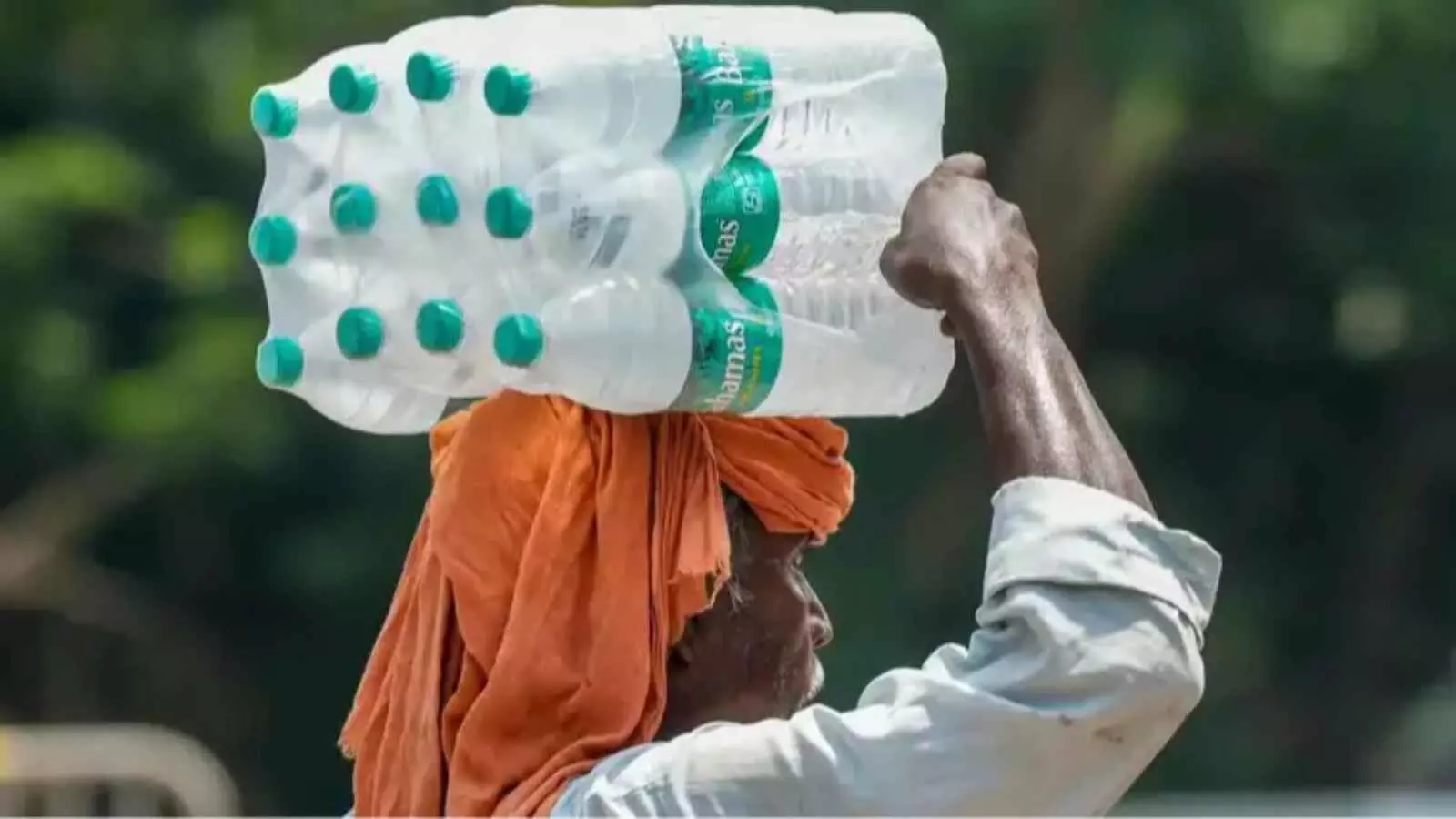 एक व्यक्ति चिलचिलाती धूप में सिर पर पानी की बोतलों का पैकेट रखकर लखनऊ की सड़क पर चल रहा है। एक व्यक्ति चिलचिलाती धूप में सिर पर पानी की बोतलों का पैकेट रखकर लखनऊ की सड़क पर चल रहा है।