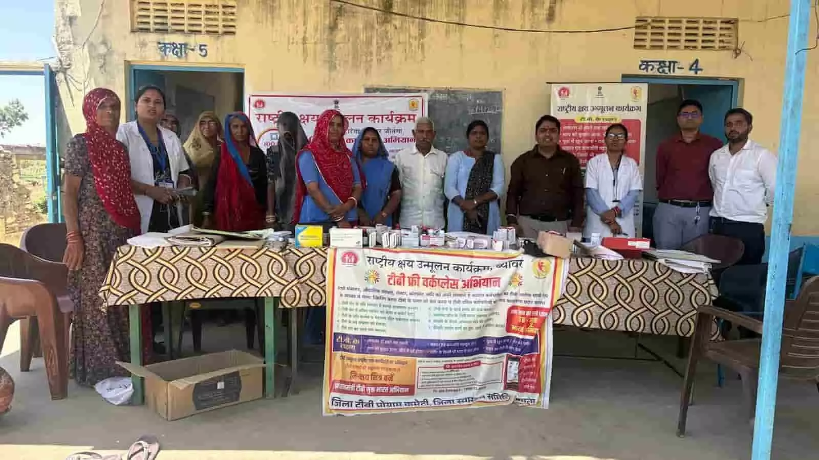 रेल मंगरा के स्वास्थ्य शिविर में बैनर के पीछे खड़े चिकित्सा कर्मी और ग्रामीण टीबी जागरूकता अभियान के दौरान। रेल मंगरा के स्वास्थ्य शिविर में बैनर के पीछे खड़े चिकित्सा कर्मी और ग्रामीण टीबी जागरूकता अभियान के दौरान।