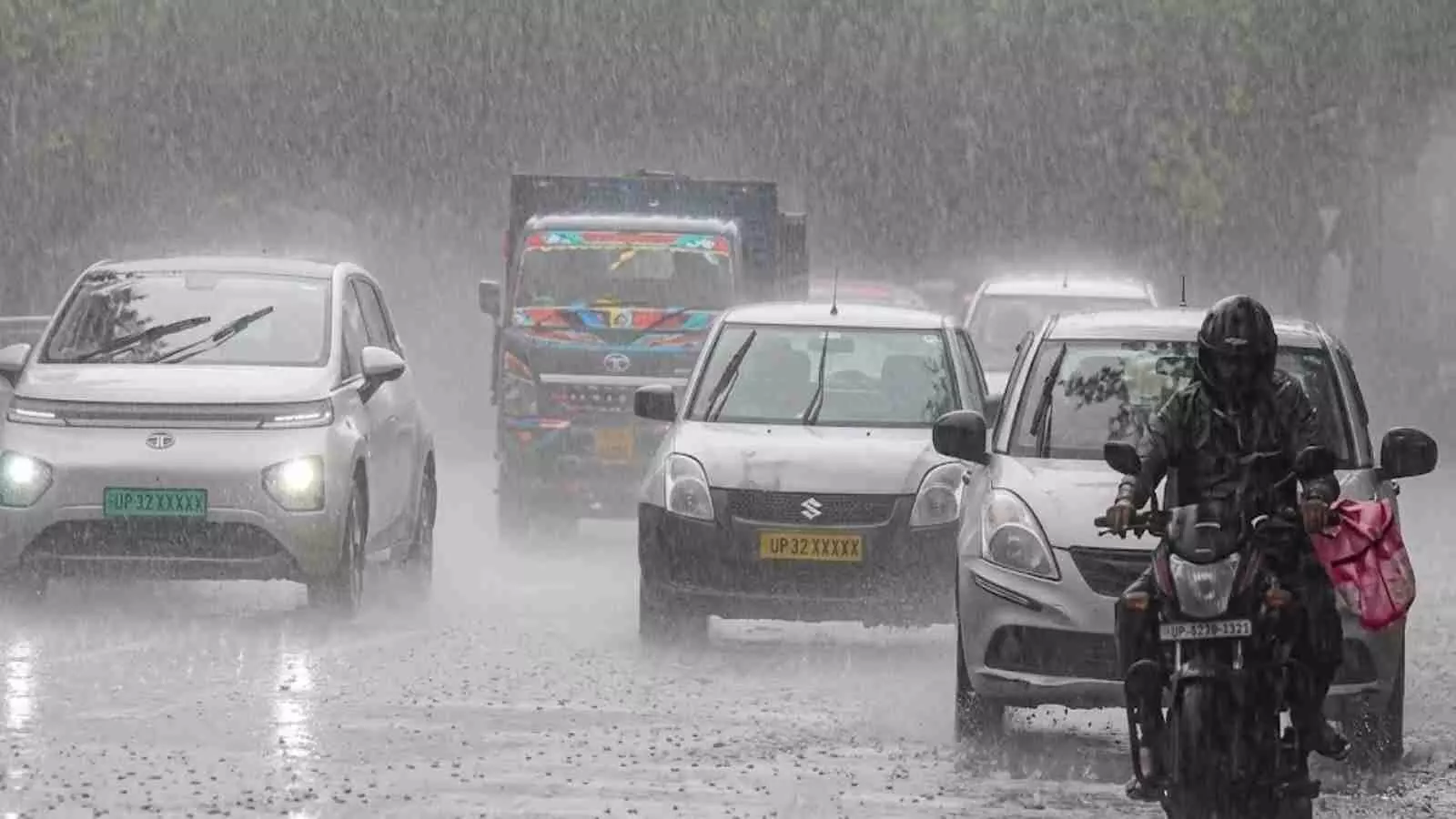 बारिश के दौरान सड़क पर चलती गाड़ियां और मोटर साइकिल चालक उत्तर भारत में मौसमी बदलाव के संदर्भ में। बारिश के दौरान सड़क पर चलती गाड़ियां और मोटर साइकिल चालक उत्तर भारत में मौसमी बदलाव के संदर्भ में।