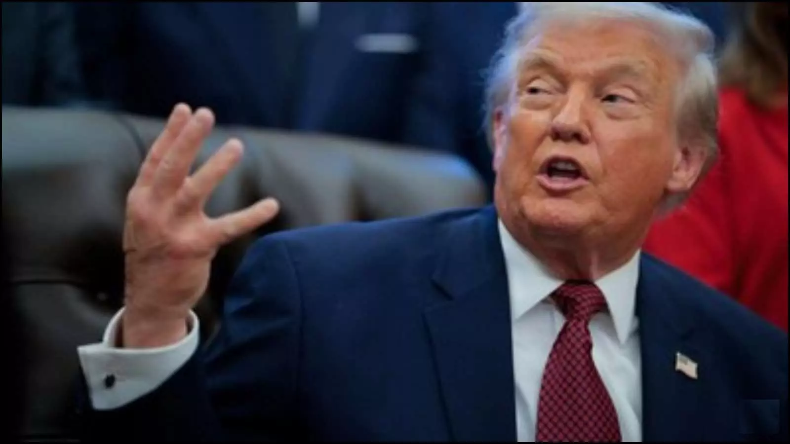 नीले सूट और लाल टाई में अमेरिकी राष्ट्रपति डोनाल्ड ट्रंप हाथ के इशारे से बात करते हुए।