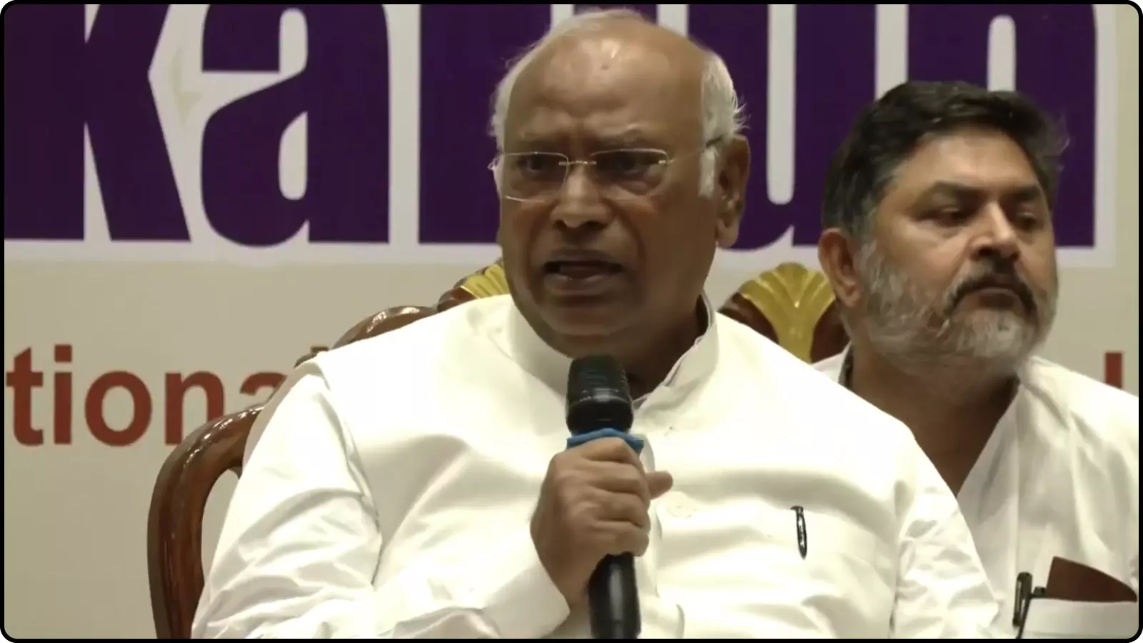 माइक पकड़े हुए मल्लिकार्जुन खरगे सफेद कुर्ते में एक प्रेस कॉन्फ्रेंस के दौरान चेन्नई में।