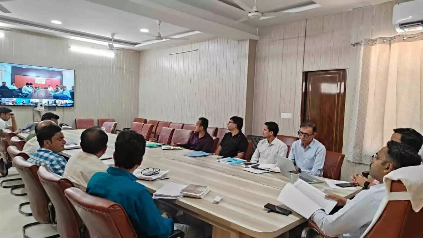 कॉन्फ्रेंस हॉल में जिला कलेक्टर और अधिकारी मीटिंग टेबल पर विकसित ग्राम अभियान की समीक्षा करते हुए।