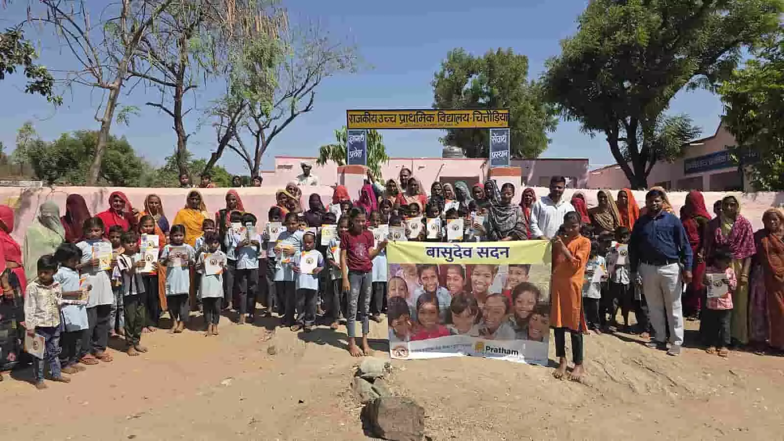राजकीय उच्च प्राथमिक विद्यालय चितौड़िया में मदर्स वर्कशॉप के दौरान बैनर लेकर खड़े बच्चे और ग्रामीण महिलाएं।
