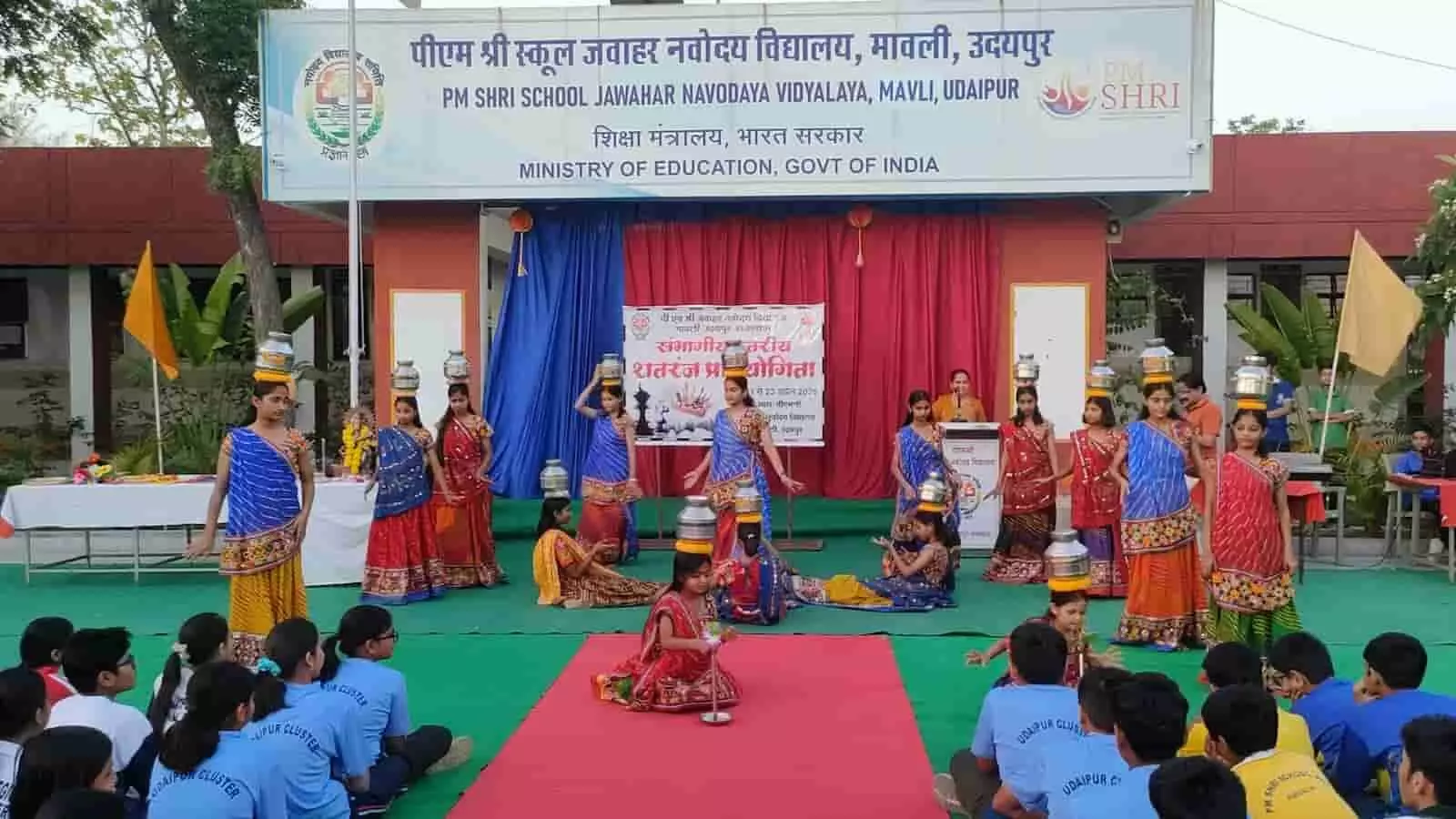 जेएनवी मावली में शतरंज प्रतियोगिता के समापन पर चरी नृत्य करती छात्राएं और बैठे हुए अन्य विद्यार्थी। जेएनवी मावली में शतरंज प्रतियोगिता के समापन पर चरी नृत्य करती छात्राएं और बैठे हुए अन्य विद्यार्थी।