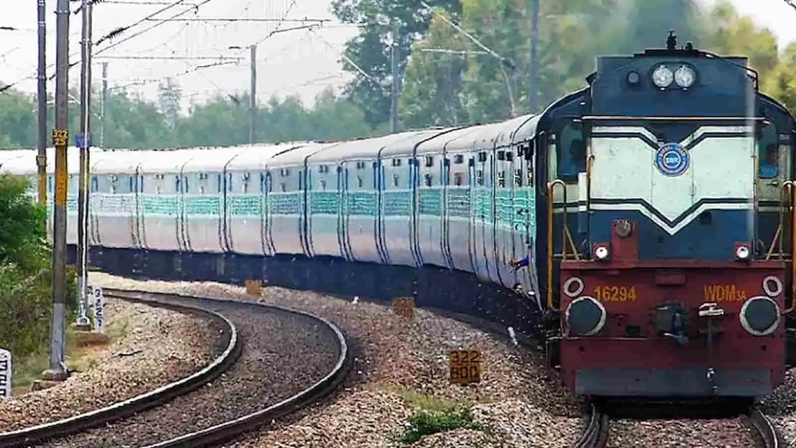 पटरी पर दौड़ती नीले रंग की डीजल इंजन वाली भारतीय ट्रेन और आसपास फैली हरियाली। पटरी पर दौड़ती नीले रंग की डीजल इंजन वाली भारतीय ट्रेन और आसपास फैली हरियाली।