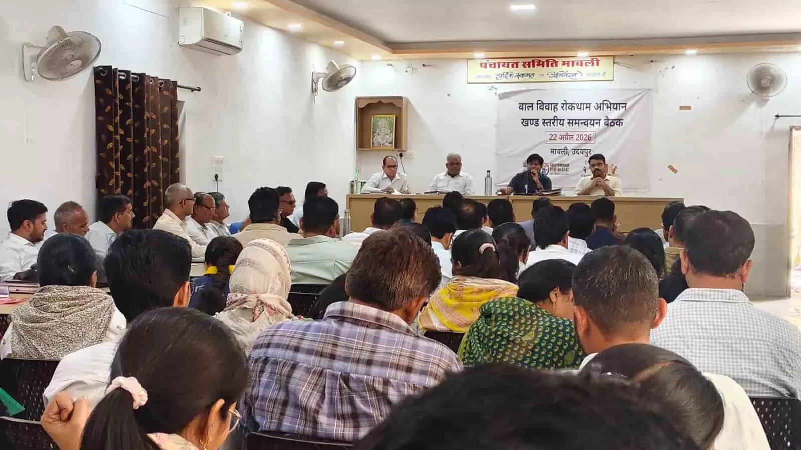 मावली पंचायत समिति सभागार में बाल विवाह रोकथाम बैठक के दौरान मंच पर बैठे अधिकारी और उपस्थित जनसमूह। मावली पंचायत समिति सभागार में बाल विवाह रोकथाम बैठक के दौरान मंच पर बैठे अधिकारी और उपस्थित जनसमूह।