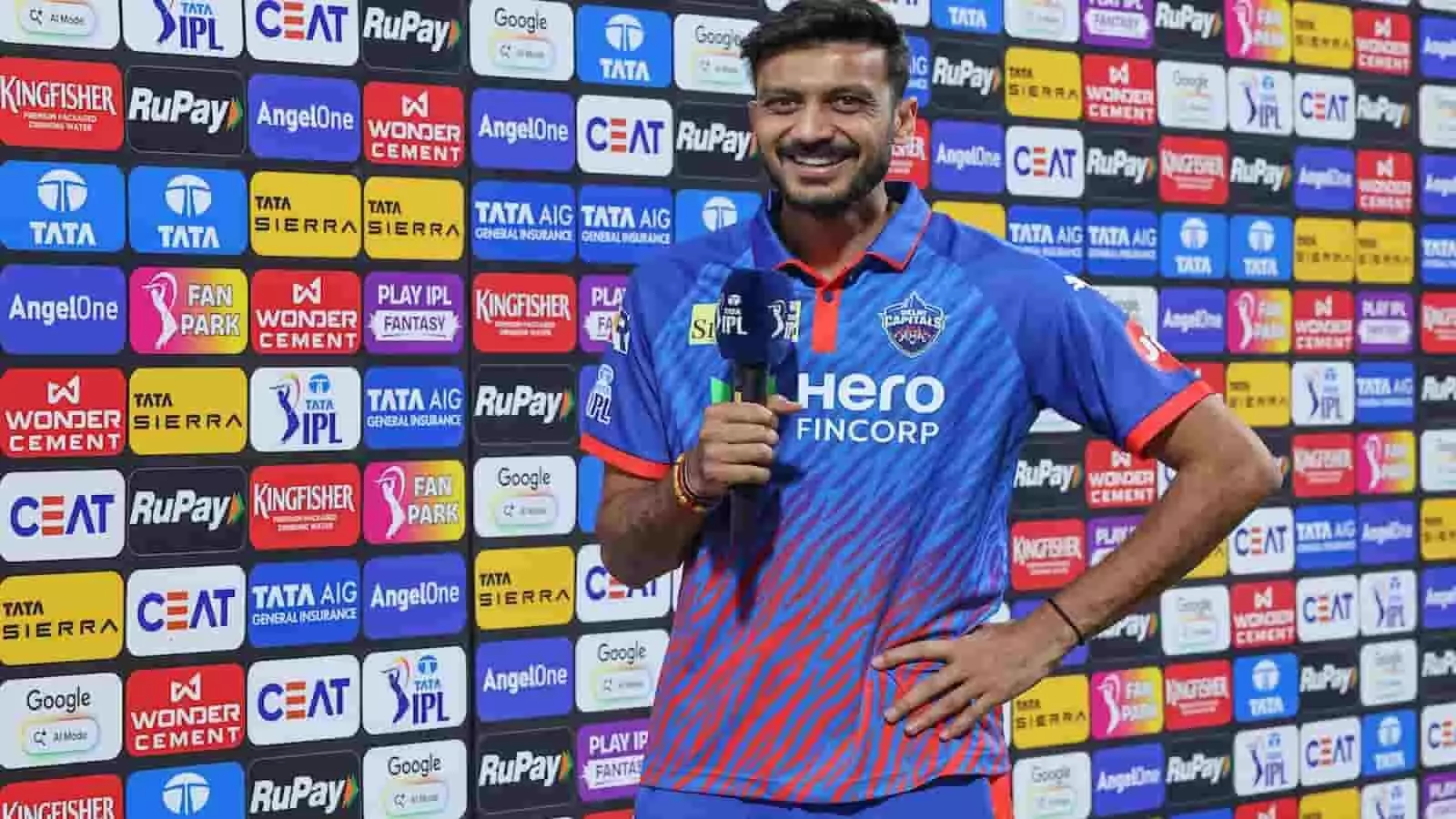 नीली जर्सी पहने और हाथ में माइक थामे मुस्कुराते हुए क्रिकेटर अक्षर पटेल विज्ञापन बोर्ड के सामने खड़े हैं। नीली जर्सी पहने और हाथ में माइक थामे मुस्कुराते हुए क्रिकेटर अक्षर पटेल विज्ञापन बोर्ड के सामने खड़े हैं।