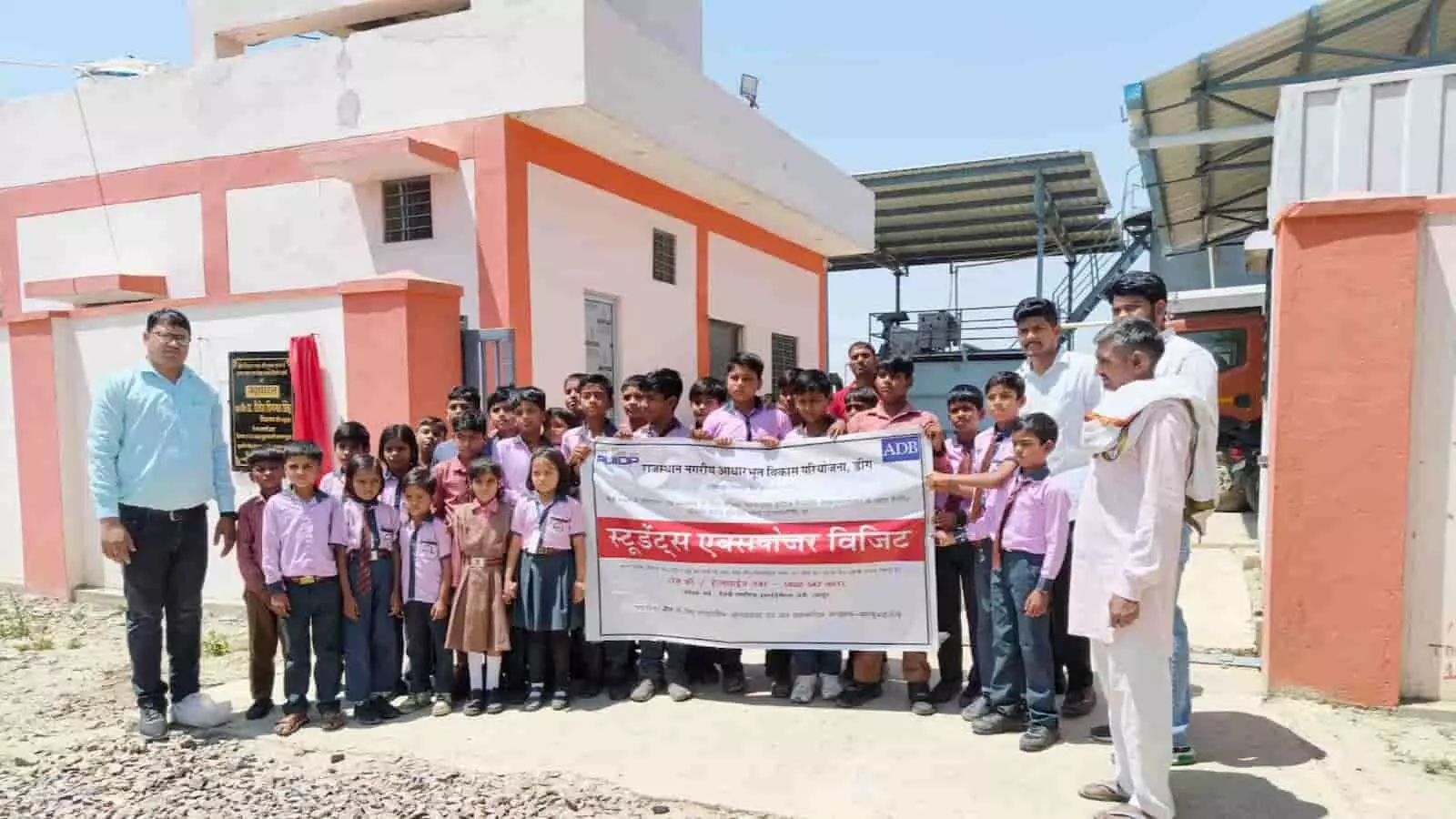 डीग में एफएसटीपी प्लांट के बाहर बैनर लेकर खड़े स्कूली छात्र और आरयूआईडीपी अधिकारी शैक्षणिक भ्रमण के दौरान। डीग में एफएसटीपी प्लांट के बाहर बैनर लेकर खड़े स्कूली छात्र और आरयूआईडीपी अधिकारी शैक्षणिक भ्रमण के दौरान।