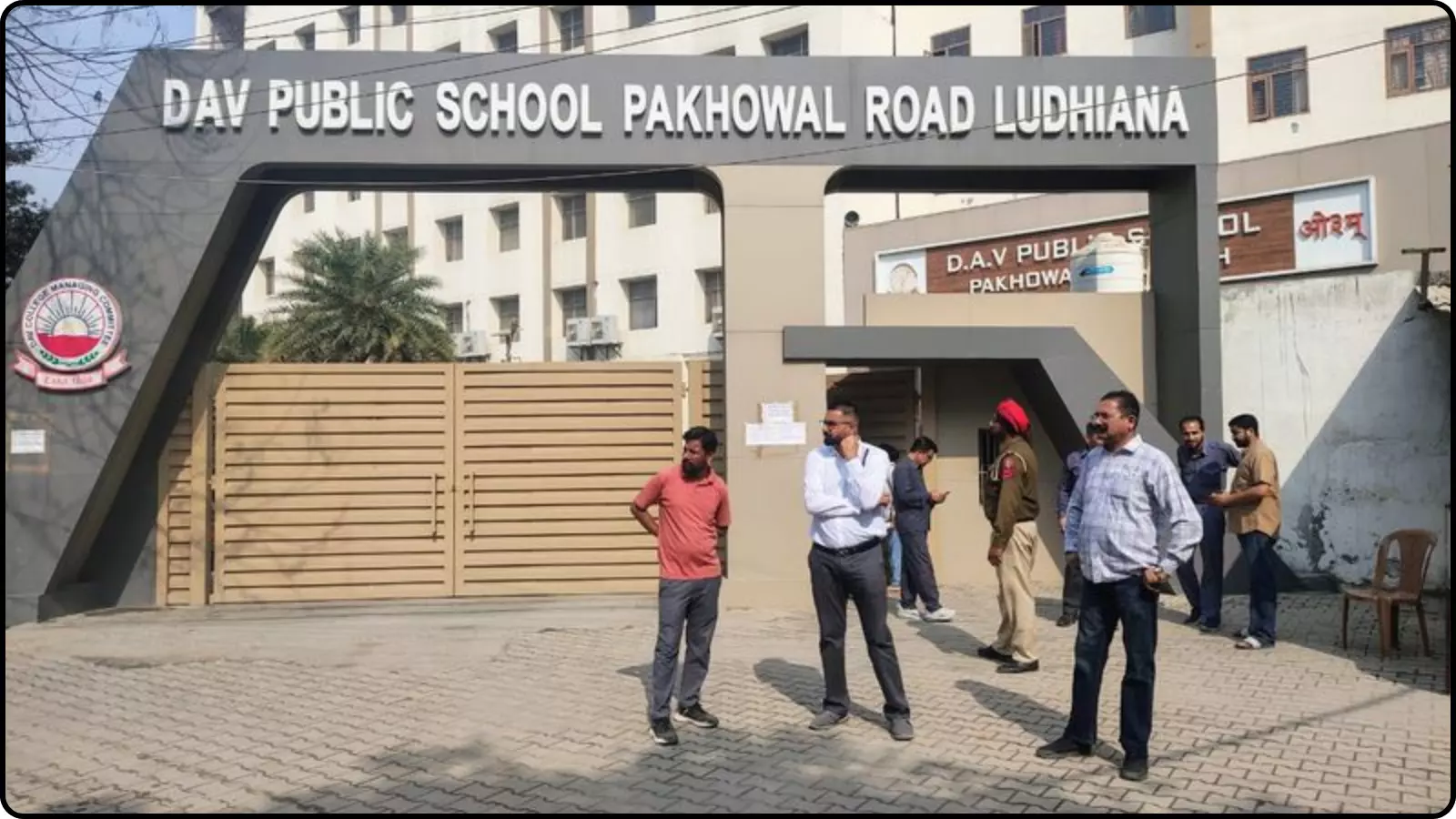 स्कूल के मुख्य प्रवेश द्वार के बाहर खड़े पुलिसकर्मी और स्थानीय लोग सुरक्षा जांच के दौरान। स्कूल के मुख्य प्रवेश द्वार के बाहर खड़े पुलिसकर्मी और स्थानीय लोग सुरक्षा जांच के दौरान।