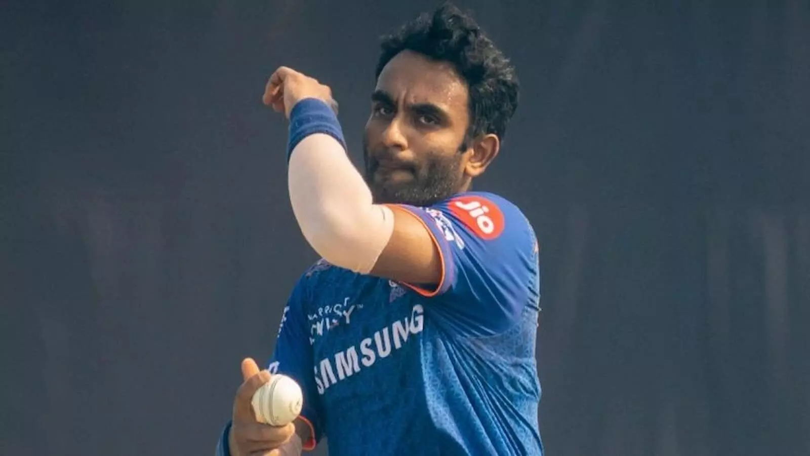 नीली जर्सी पहने क्रिकेटर जयंत यादव खेल के मैदान पर क्रिकेट की गेंद से ऑफ स्पिन गेंदबाजी कर रहे हैं।