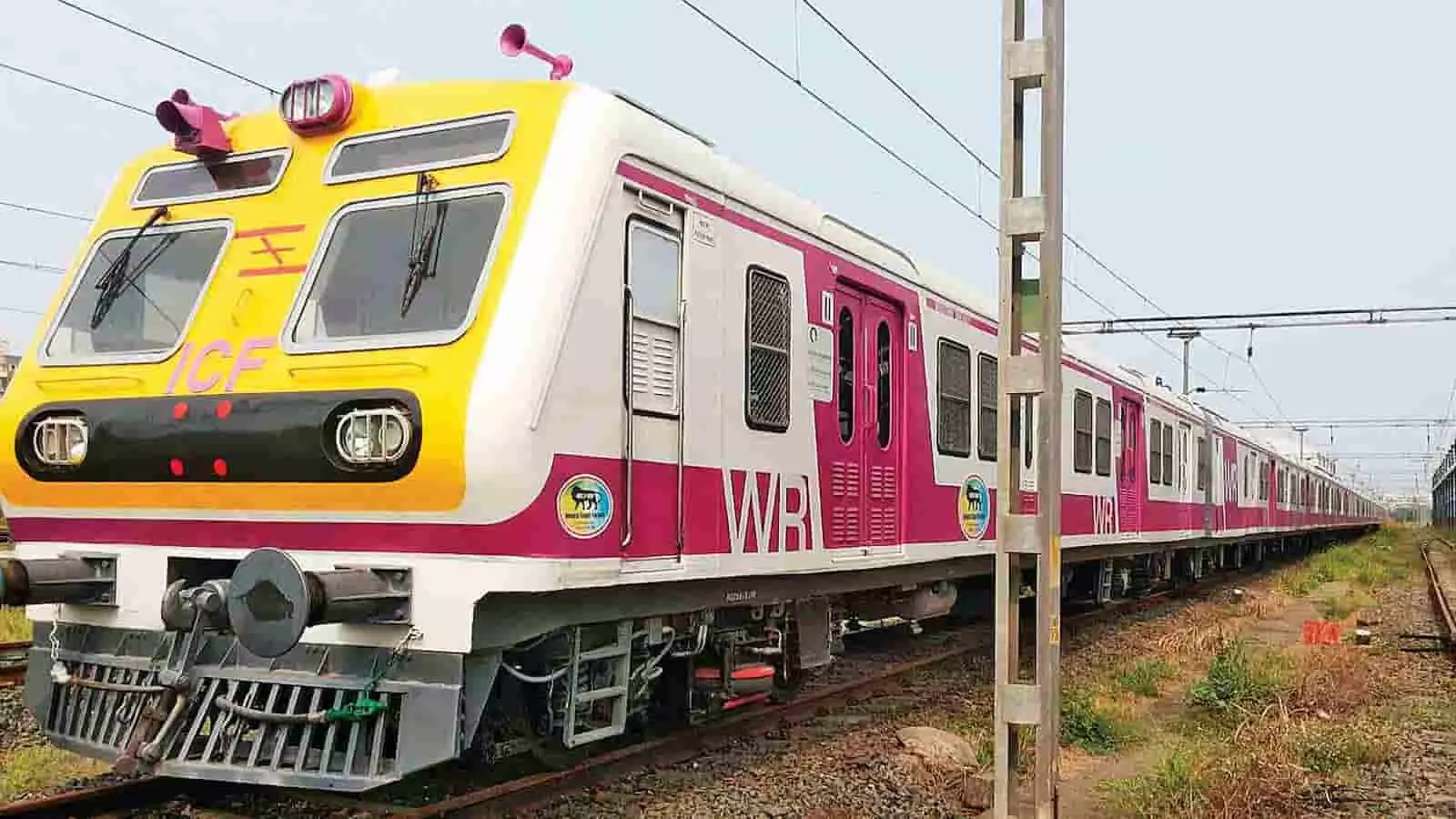 पटरी पर खड़ी पश्चिम रेलवे की पीली और सफेद रंग की ईएमयू लोकल ट्रेन का दृश्य।